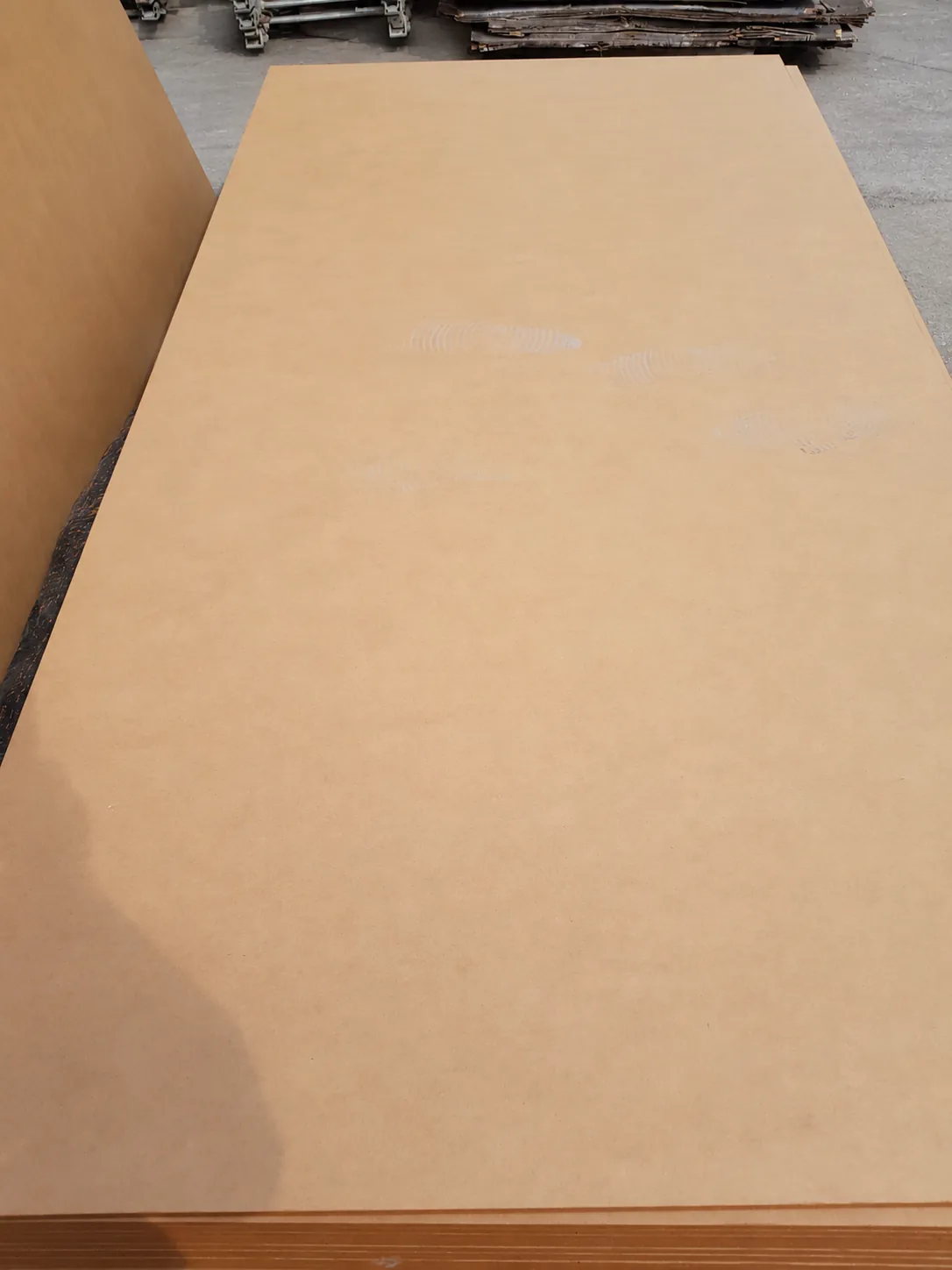 Plain MDF sheets stacked in the workshop, showing the brown face and board edges.